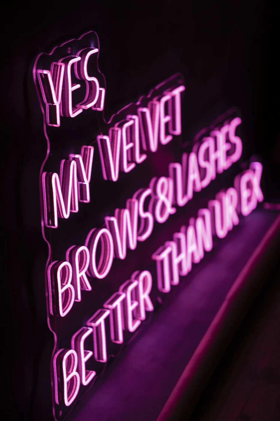 Pink LED neon lettering on a brows and lashes studio wall