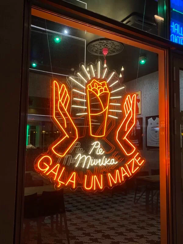 Orange LED neon hand-and-heart sign in a bistro