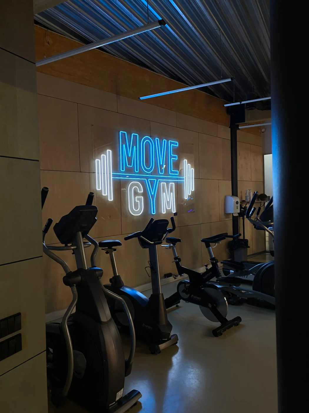 Blue LED neon logo above treadmills in a gym