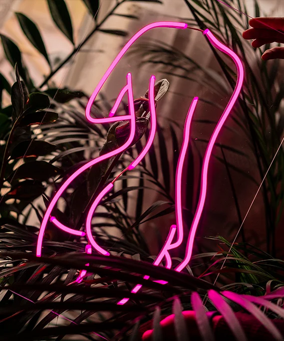 Pink LED neon line-art figure among houseplants