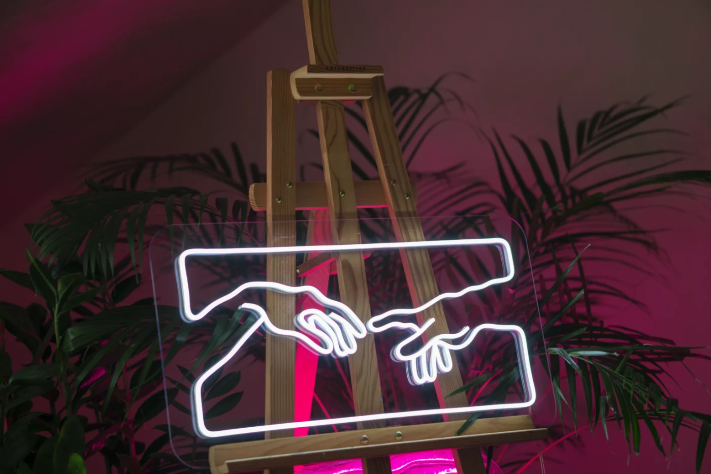 White LED neon Creation of Adam hands on an easel