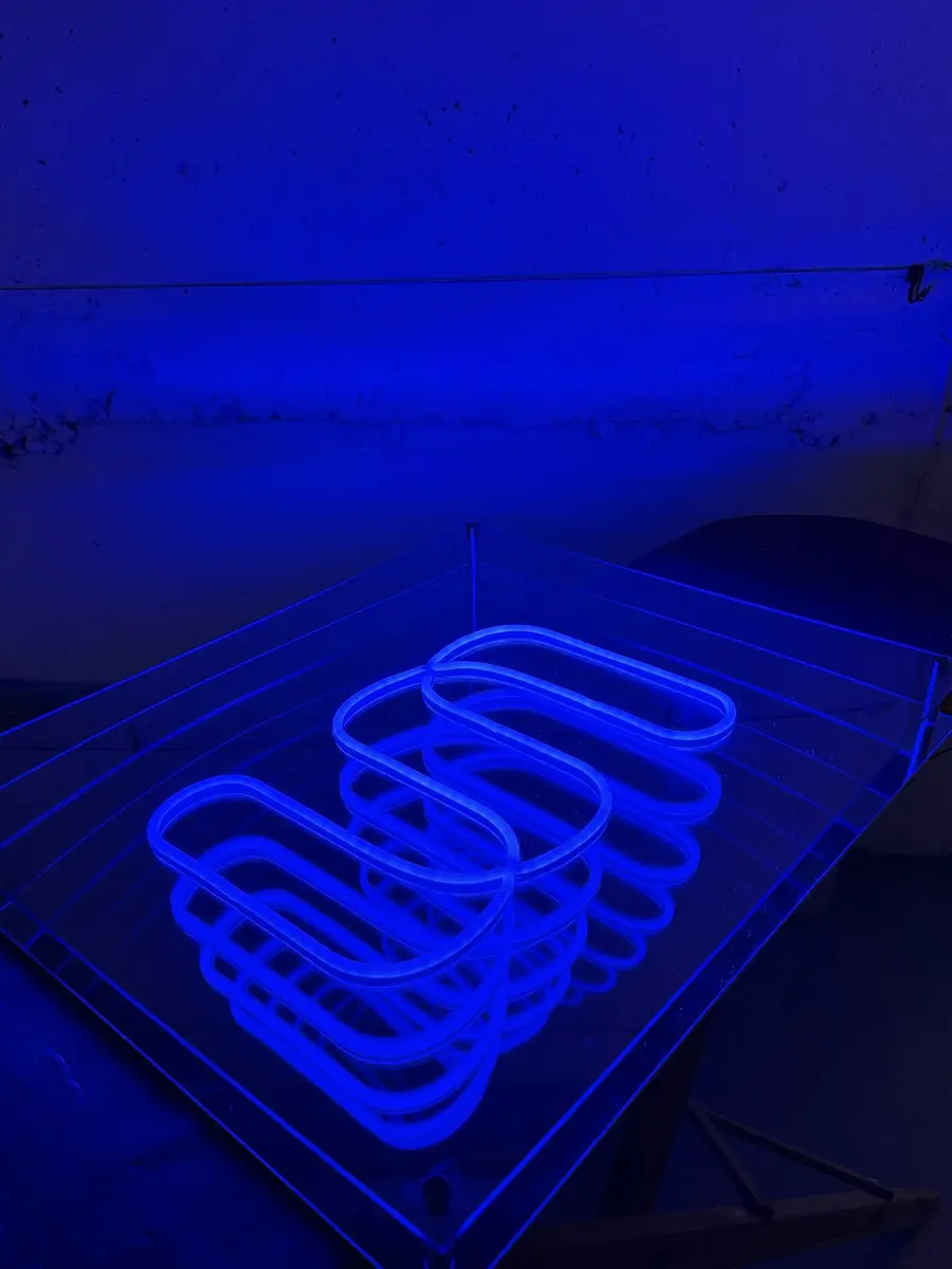 Infinity mirror neon sign in an acrylic frame, lit in blue in a dark room