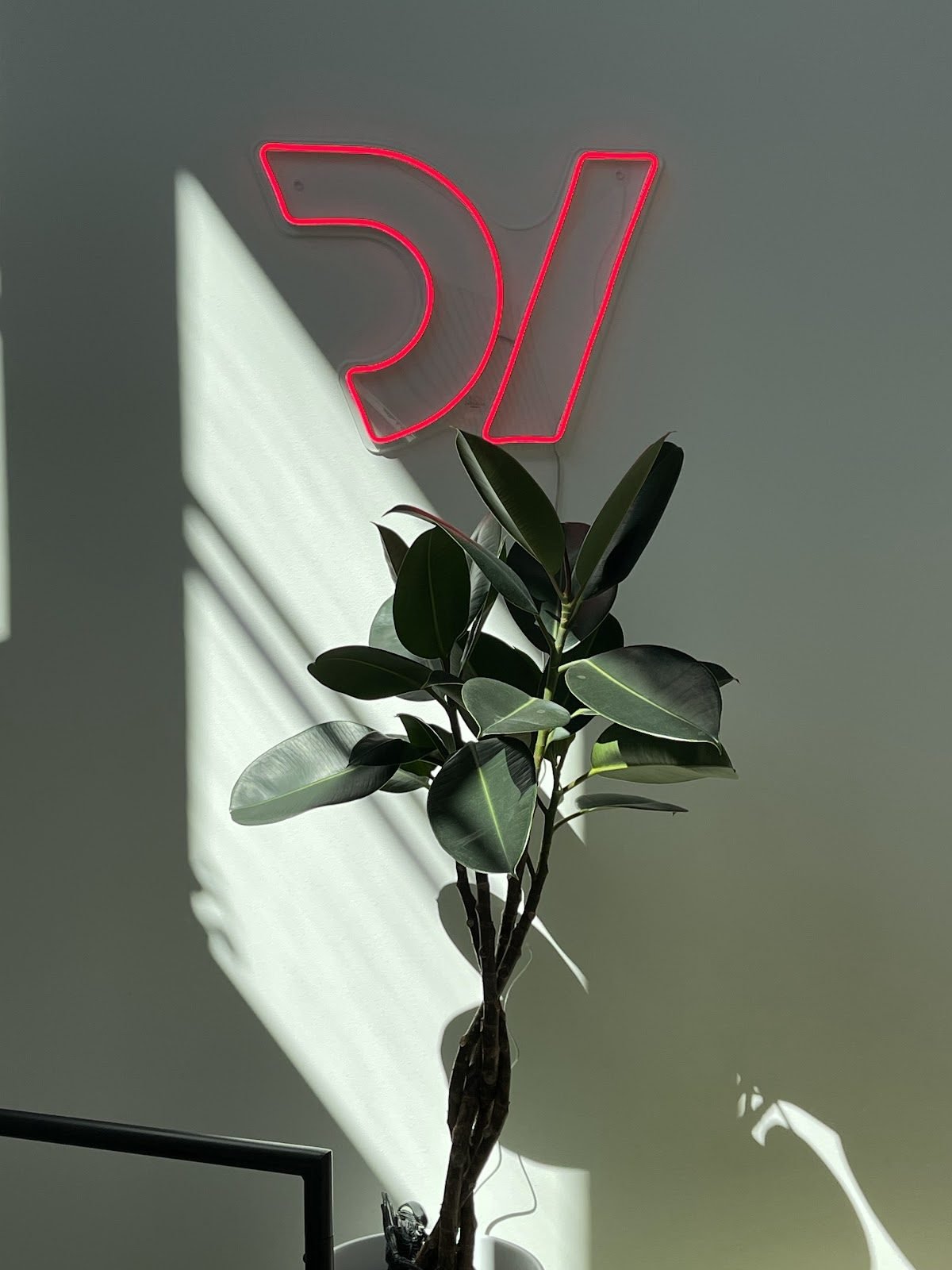 Red neon logo on a sunlit wall