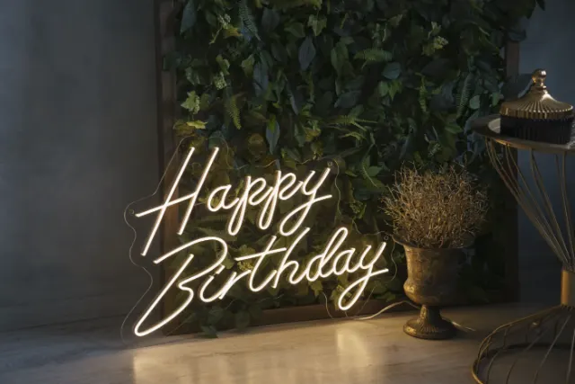 Warm white LED neon Happy Birthday sign on a greenery wall