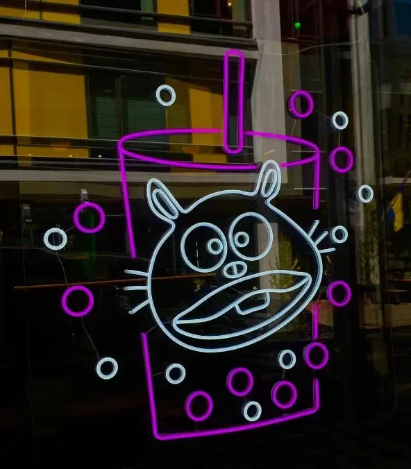 Pink LED neon cat and bubble-tea cup sign in a shop window